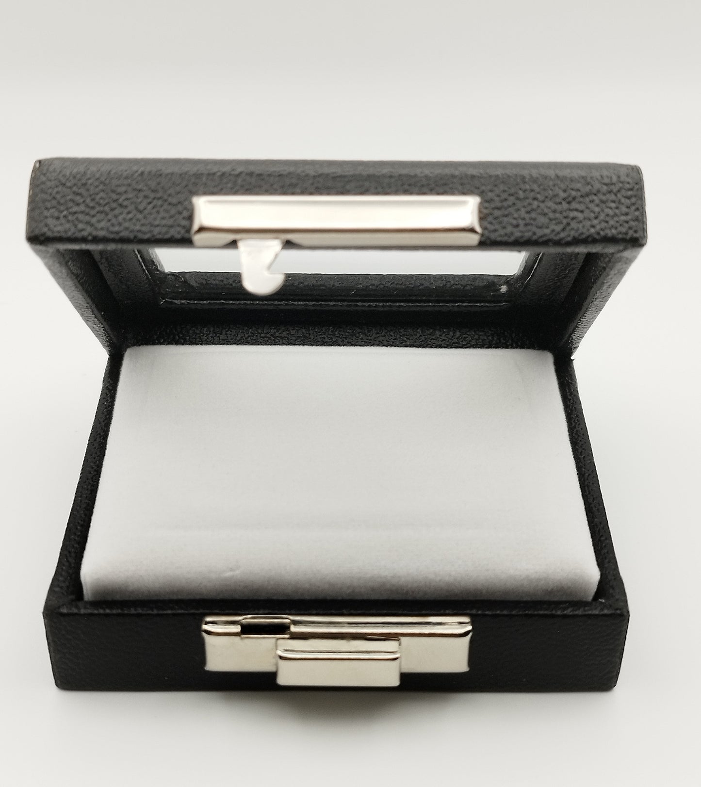 Leather-like black box with metal clasp, transparent top window, and white padded cushion. (7,5 * 6 * 2,5 cm)