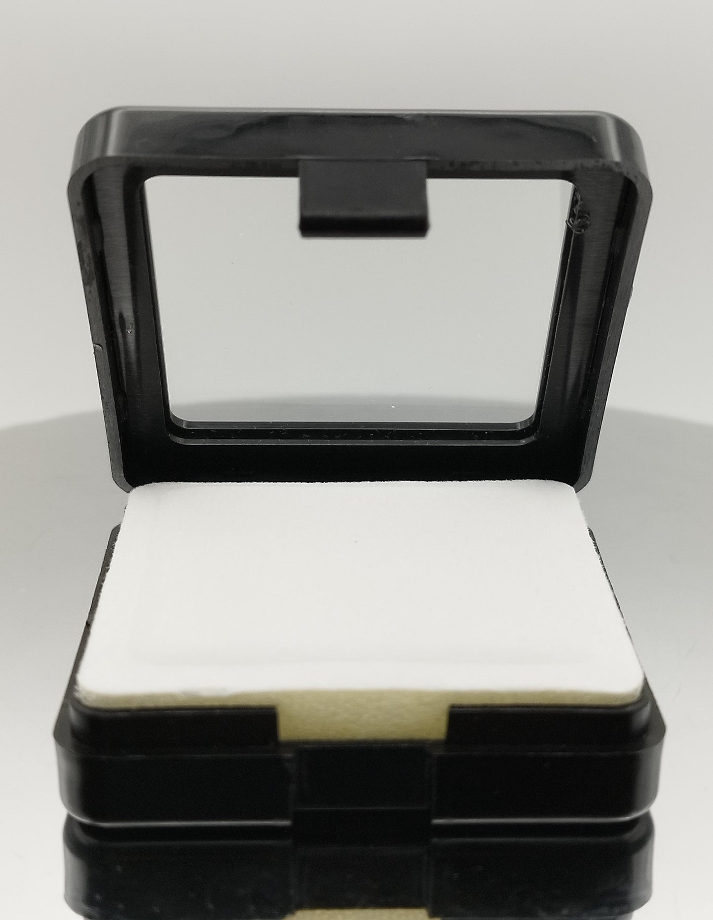 Black plastic box with window and white pad (5,4 * 5,4 * 1,6 cm)