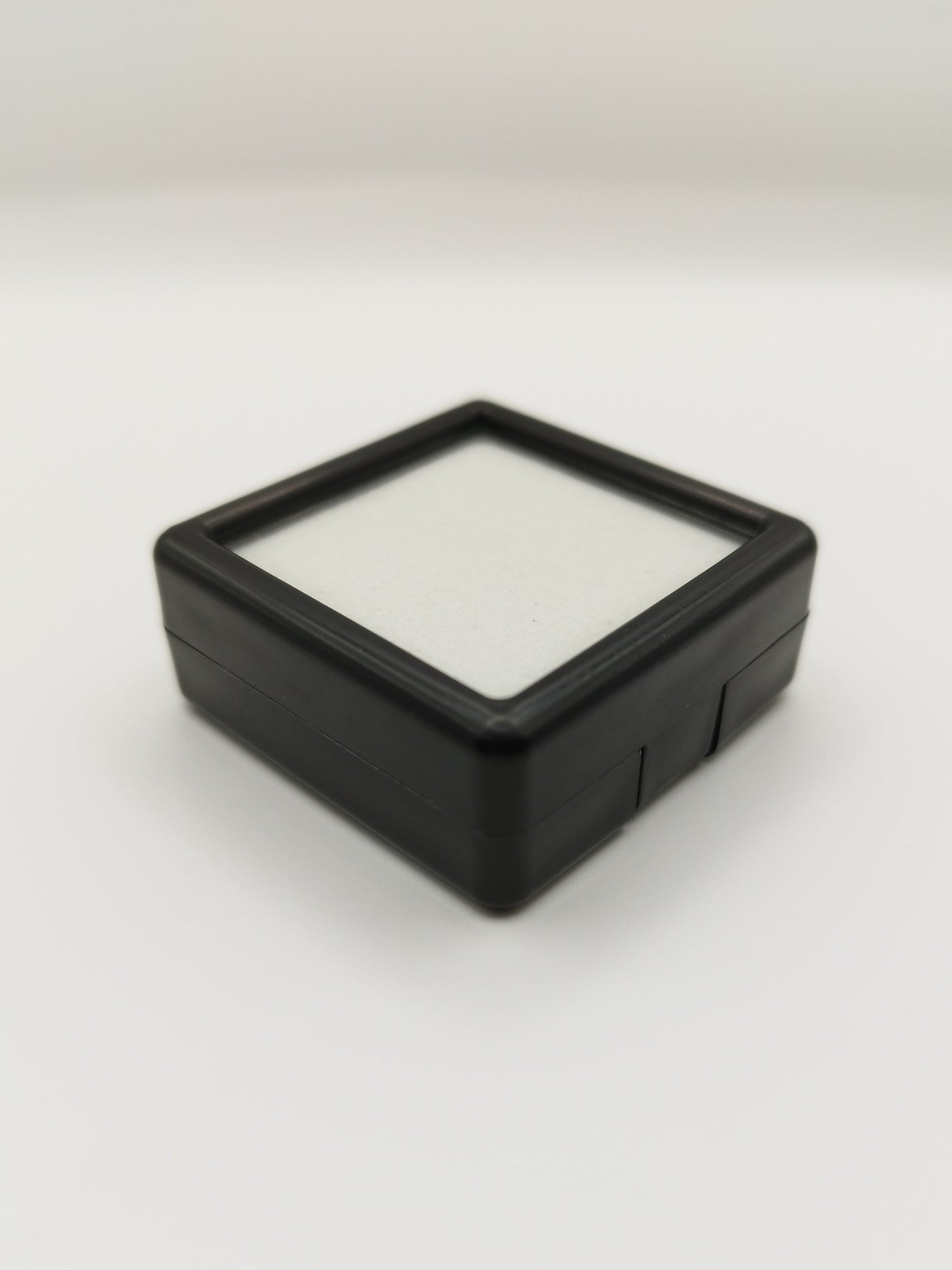 Black plastic box with window and white pad (4* 4 * 1,7 cm)