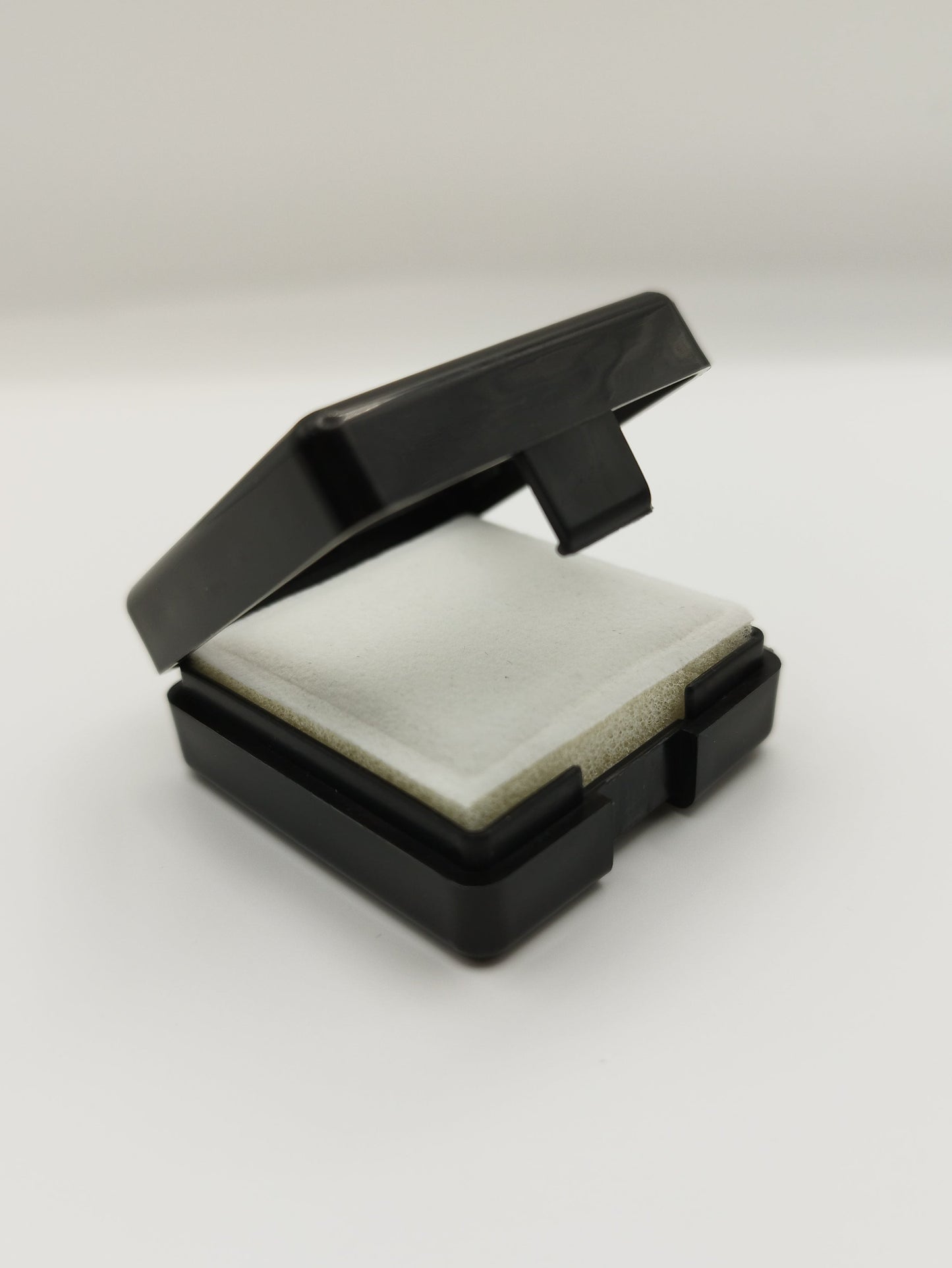 Black plastic box with window and white pad (4* 4 * 1,7 cm)