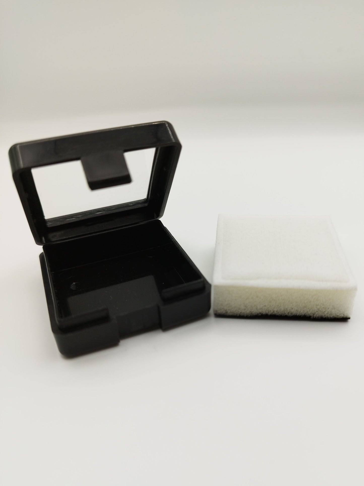Black plastic box with window and white pad (4* 4 * 1,7 cm)