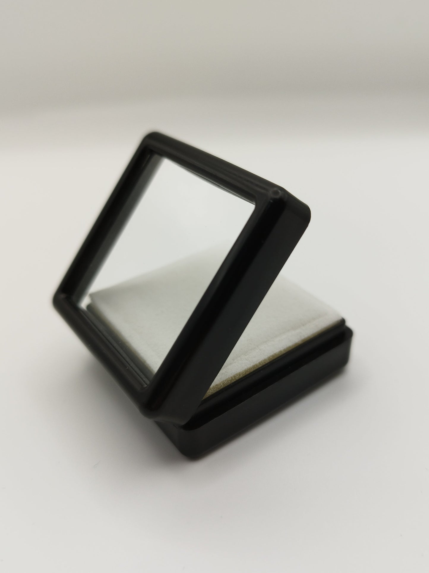 Black plastic box with window and white pad (4* 4 * 1,7 cm)