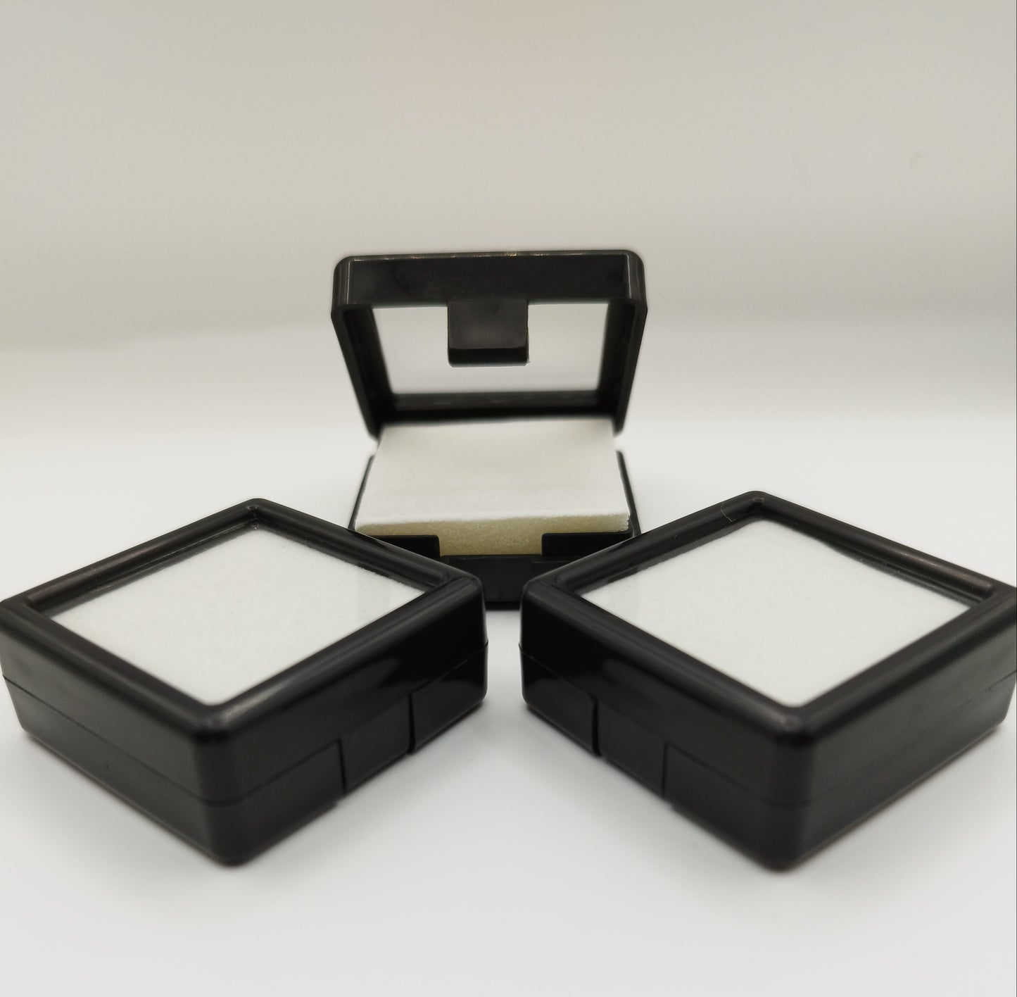 Black plastic box with window and white pad (4* 4 * 1,7 cm)